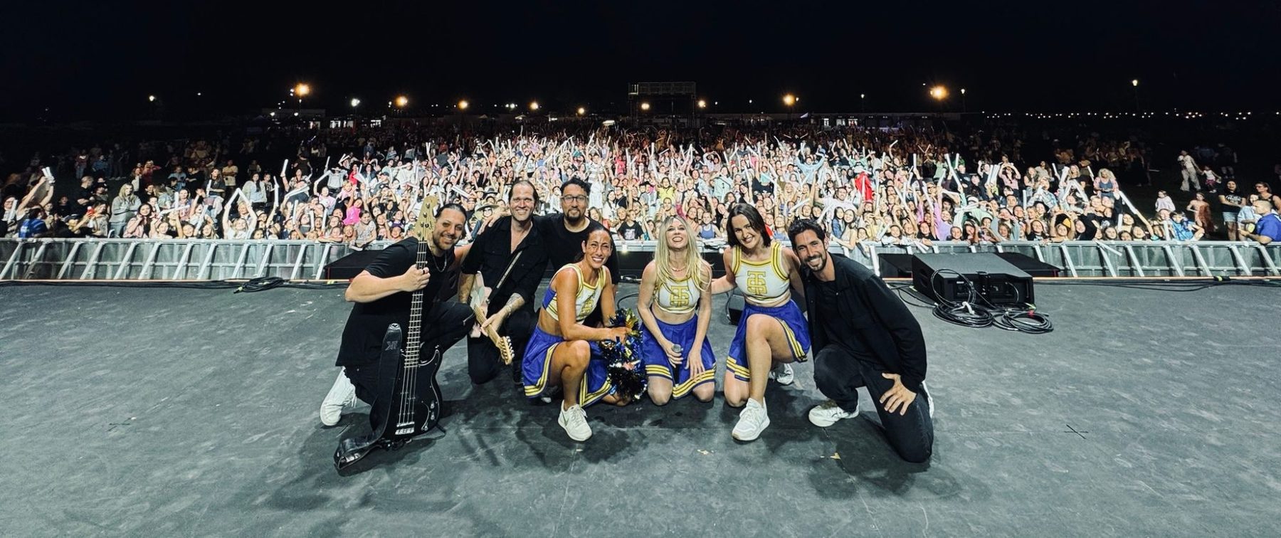 The band and dancers posing with the crowd after a show