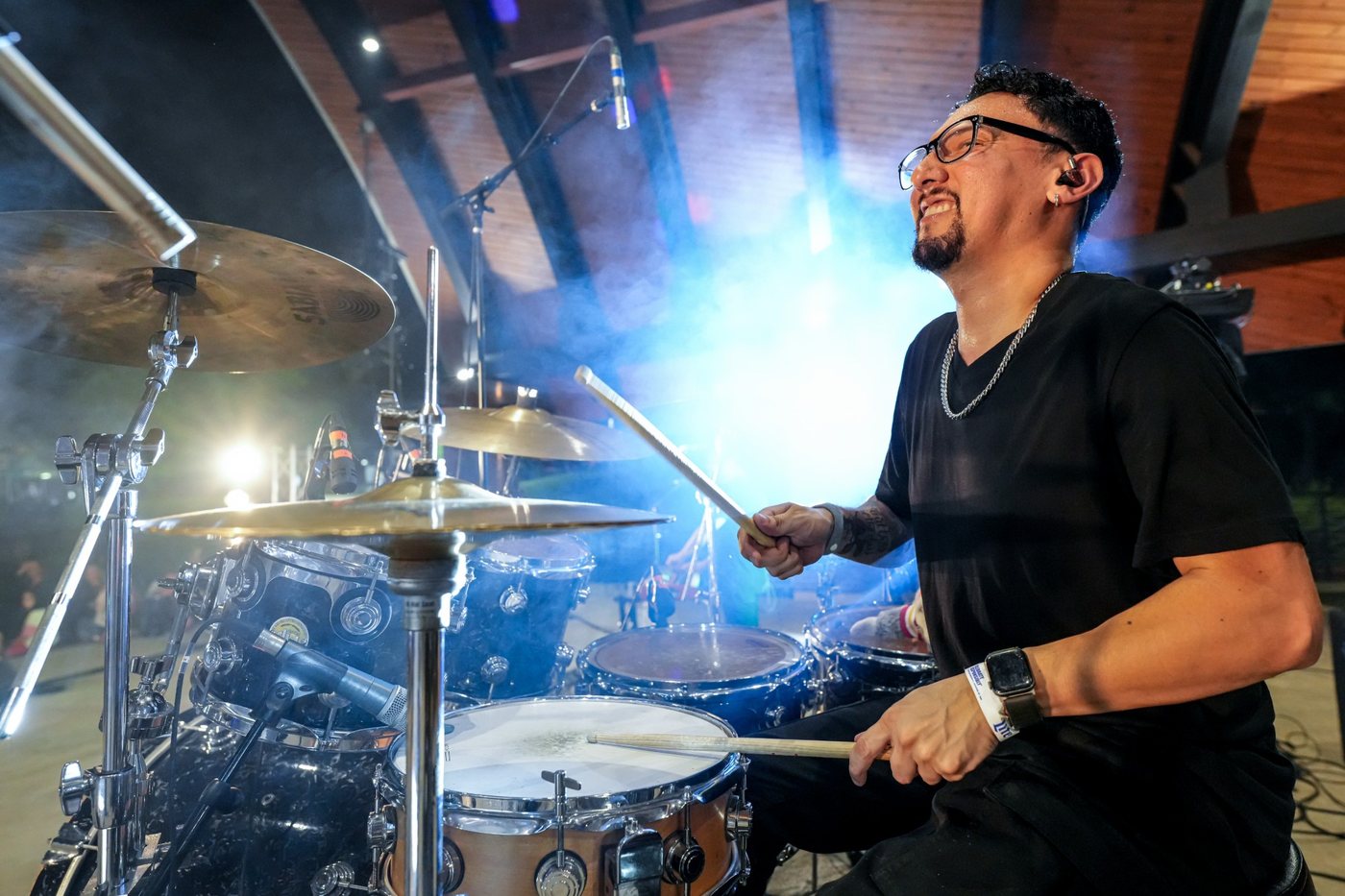 Drummer mid-hit in a haze of blue light