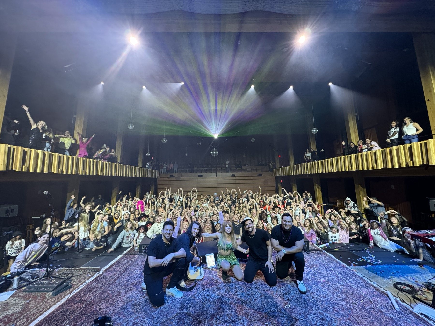 The band and Melody Ebner posing with a packed theater crowd