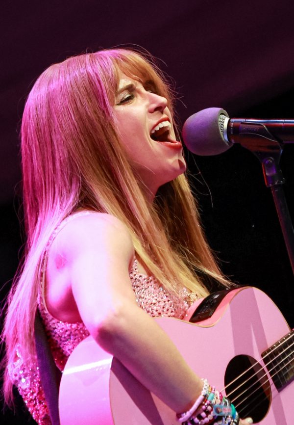 Melody Ebner singing with a pink acoustic guitar