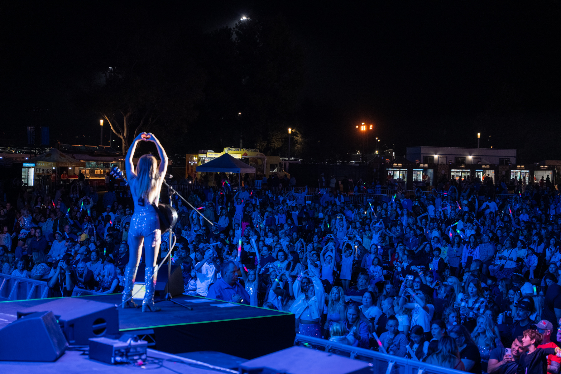 Melody Ebner on stage at Great Park Live, arms up to a packed crowd