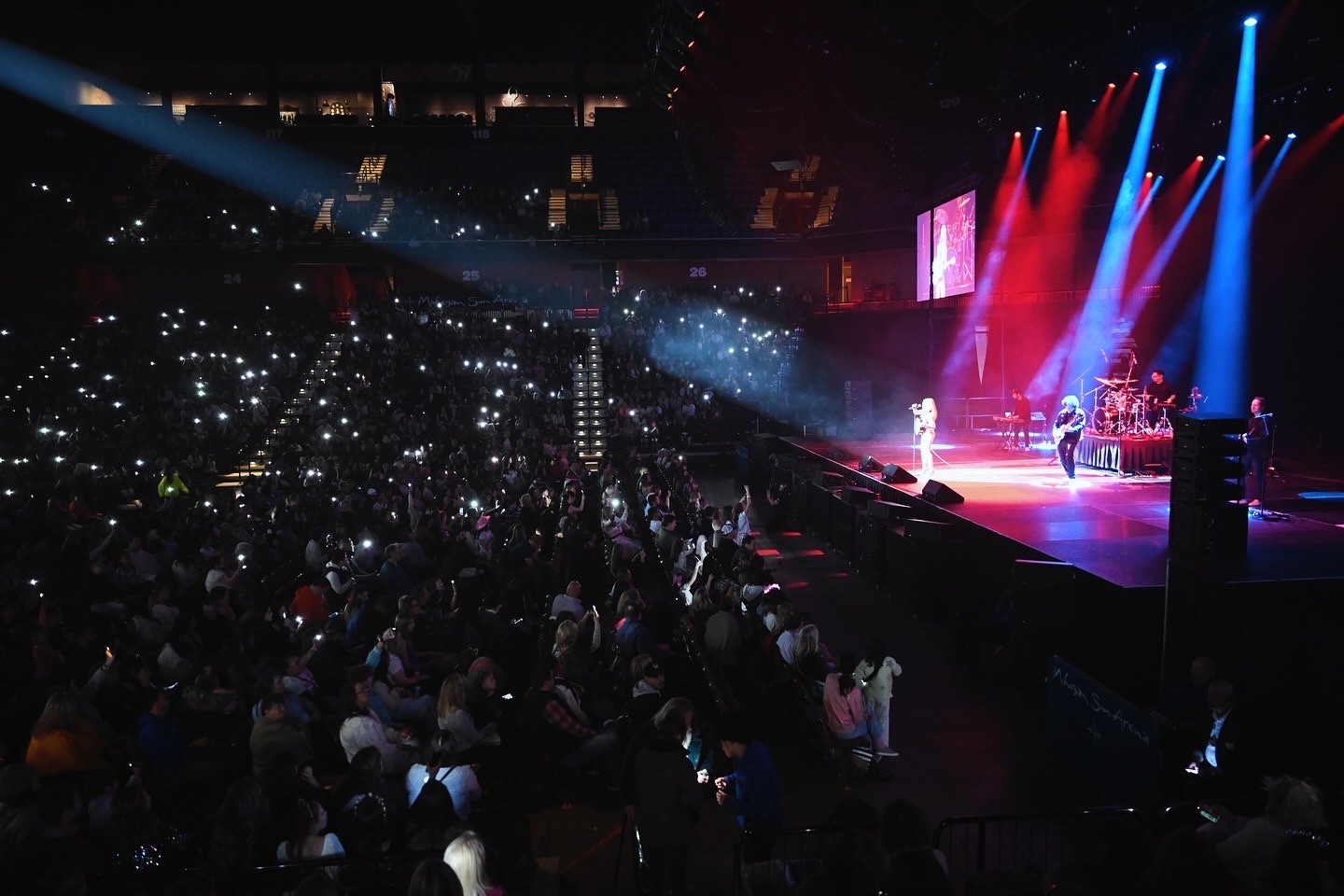 Swift Nation on stage at Mohegan Sun Arena with phone lights across the crowd