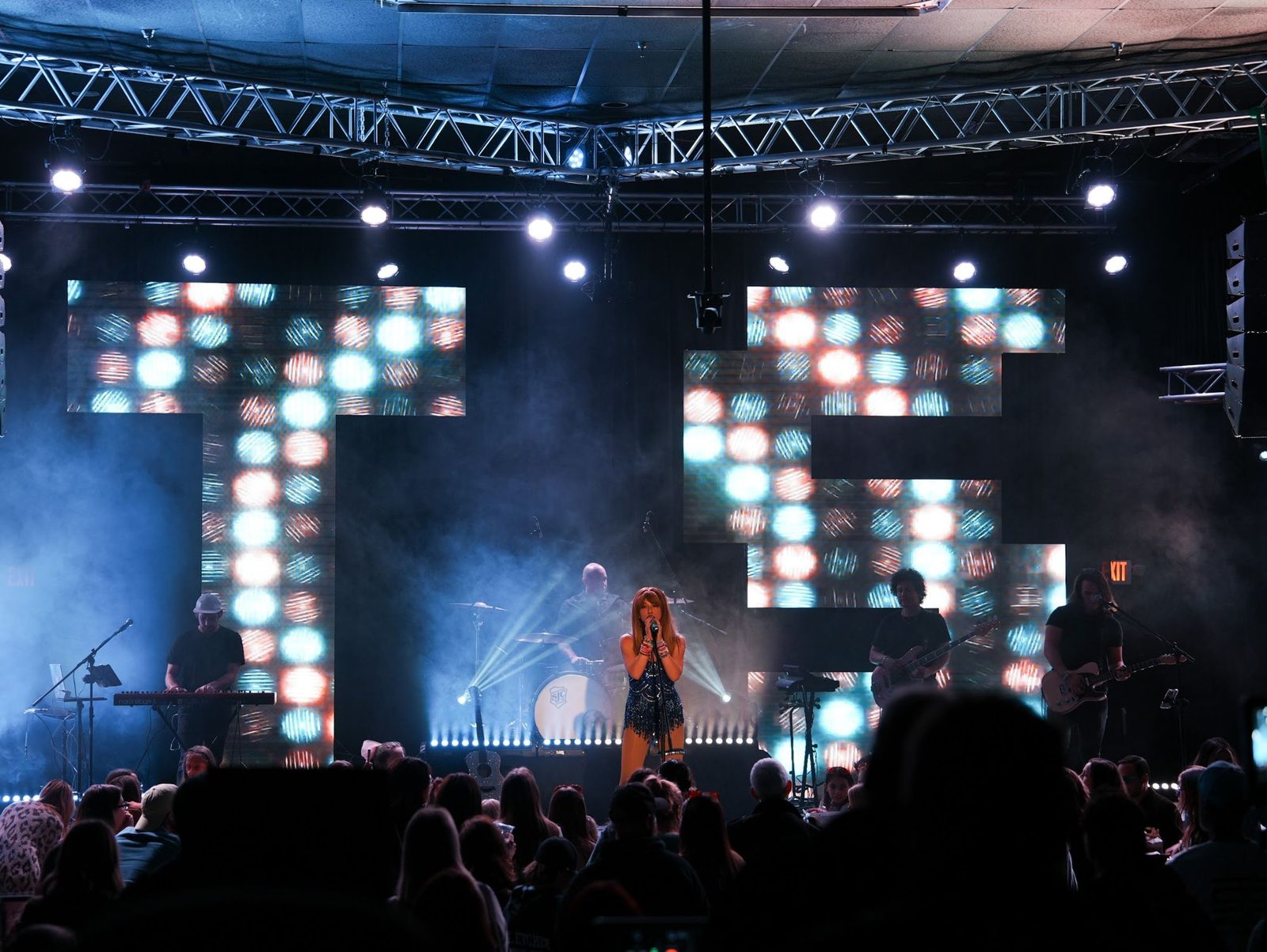 The full band on stage in front of giant LED letters